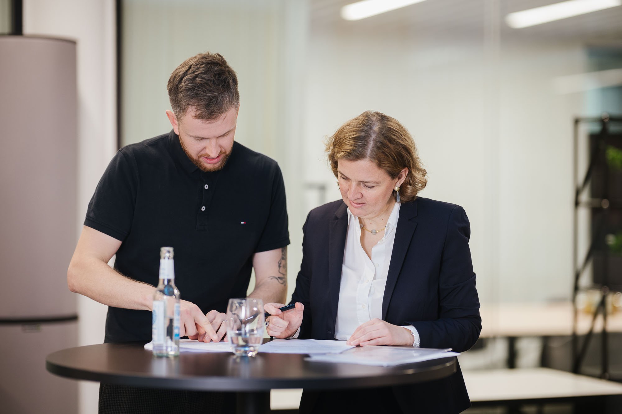 Ein Mann und eine Frau besprechen sich, stehend an einem Stehtisch.