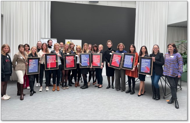 Eine Gruppe von Frauen steht zusammen und hält gerahmte Poster oder Zertifikate in den Händen.
