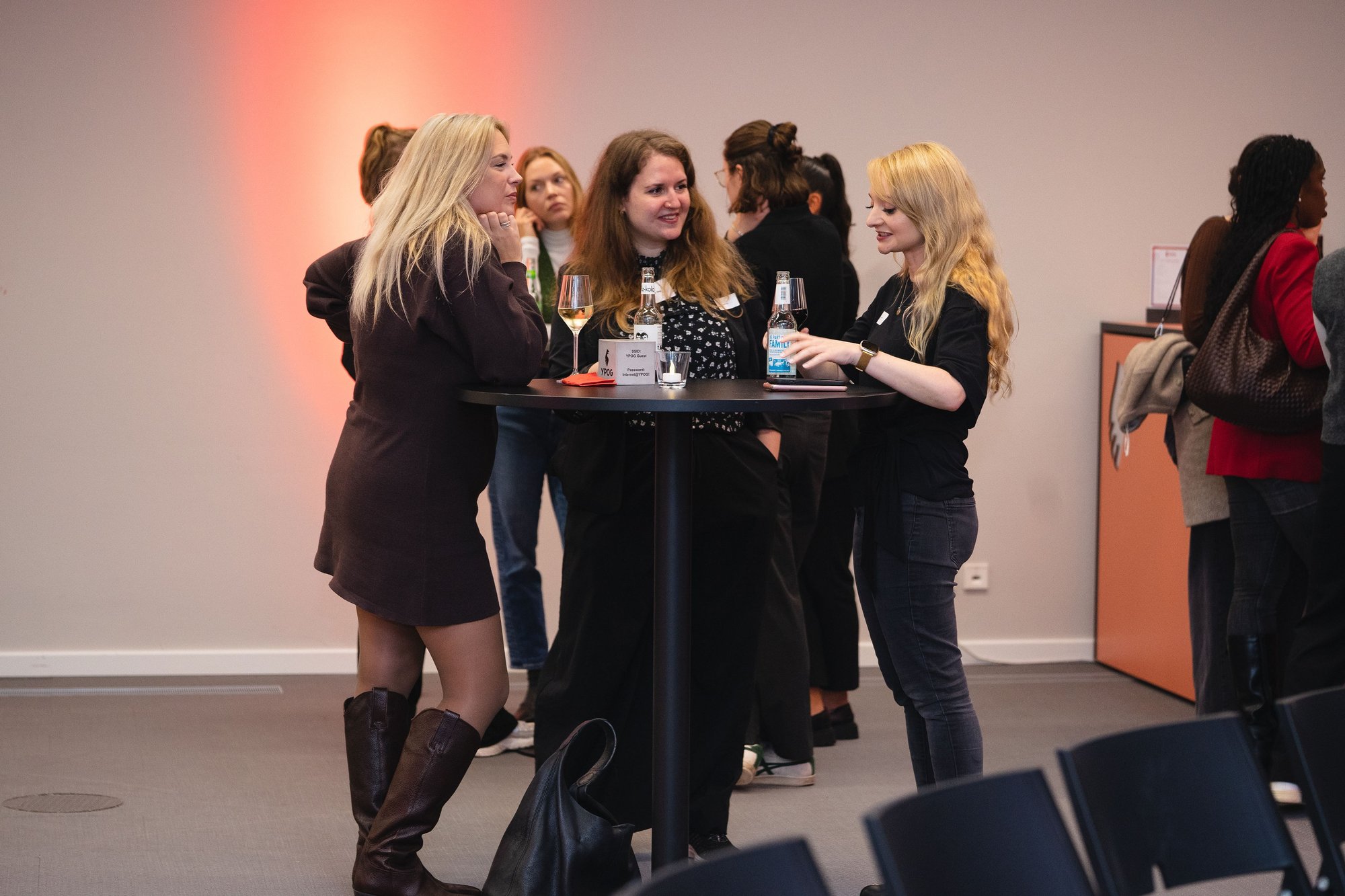 Drei Frauen stehen an einem Stehtisch und unterhalten sich