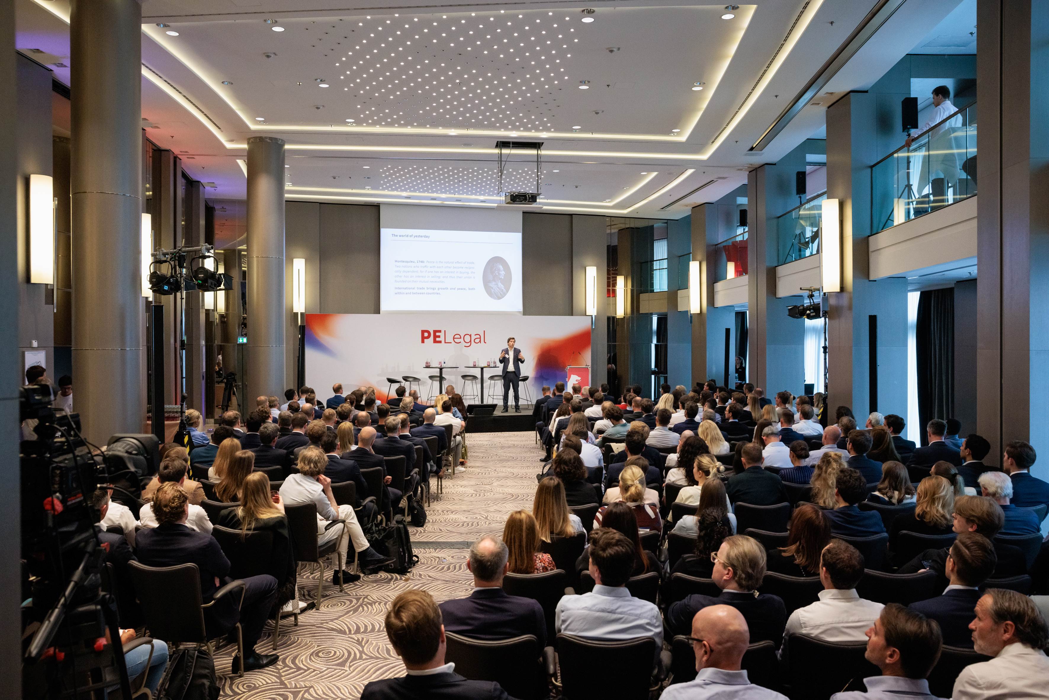 Audience-filled hall during PE Legal as a speaker presents on stage at the private equity event.